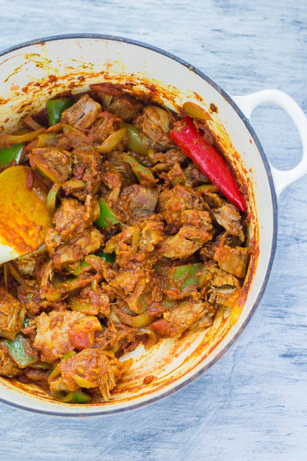 White pot full of leftover turkey curry on a blue background