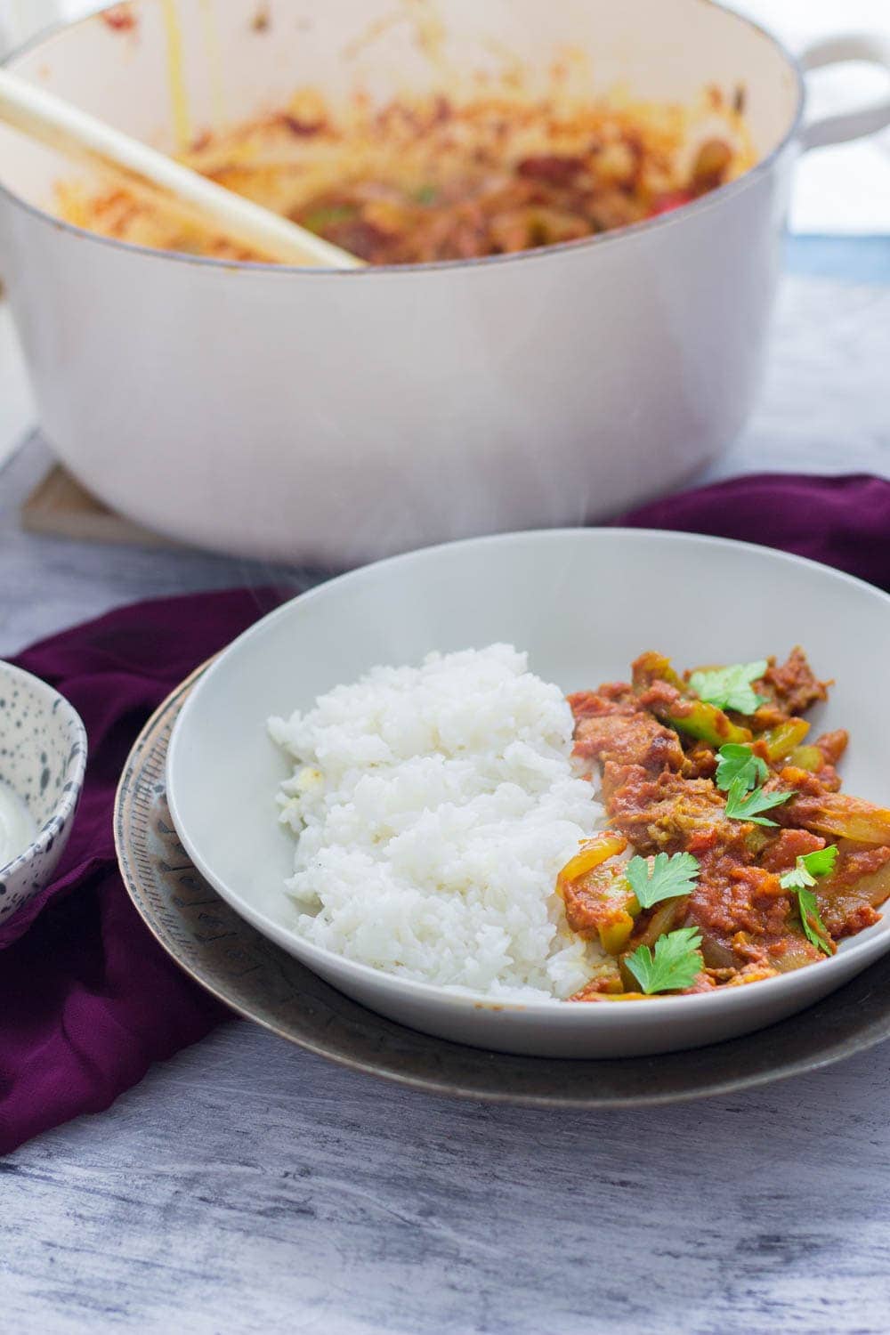 Bowl of leftover turkey curry in a metal bowl on a blue background