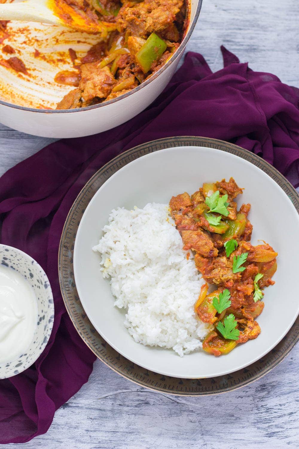 Bowl of leftover turkey curry on a blue background with purple cloth