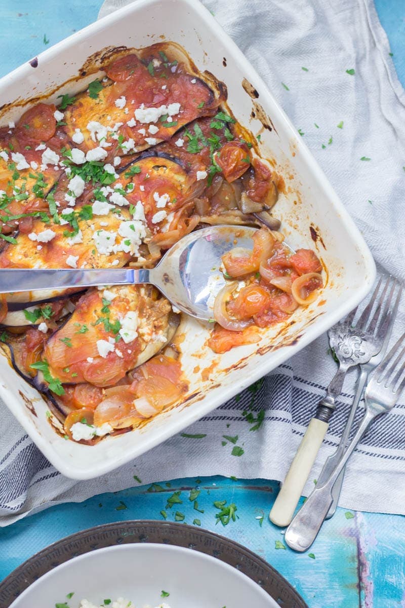 Overhead shot of baked aubergine with a spoon on a pale coloured cloth