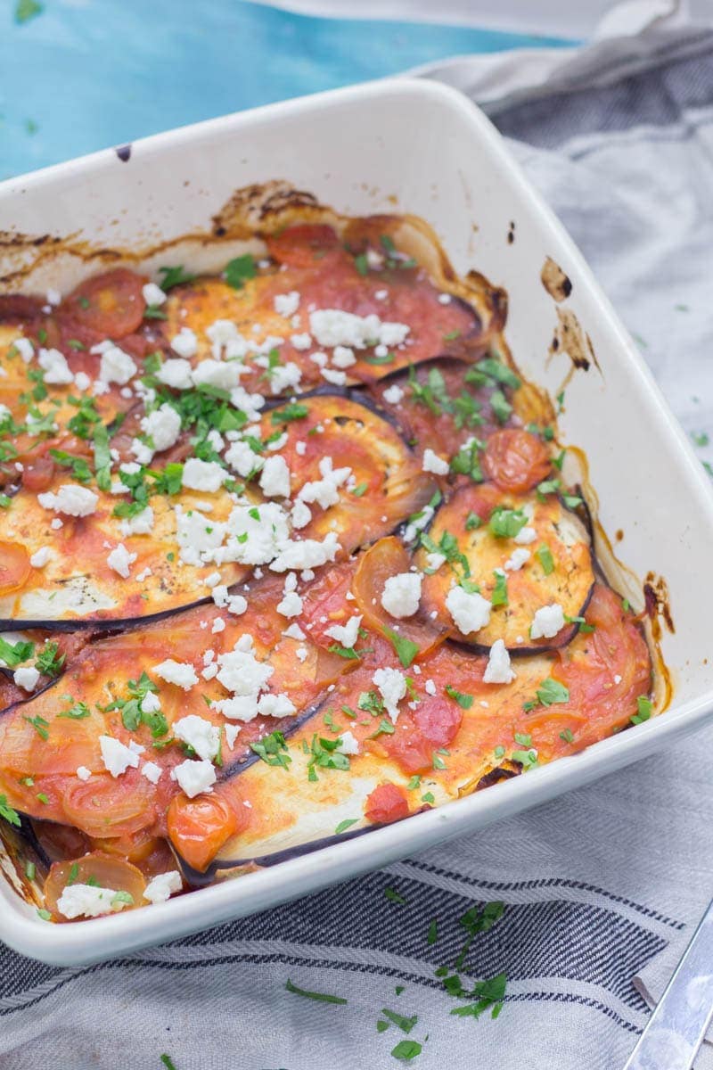 Baking dish of baked aubergine with tomato sauce sprinkled with feta