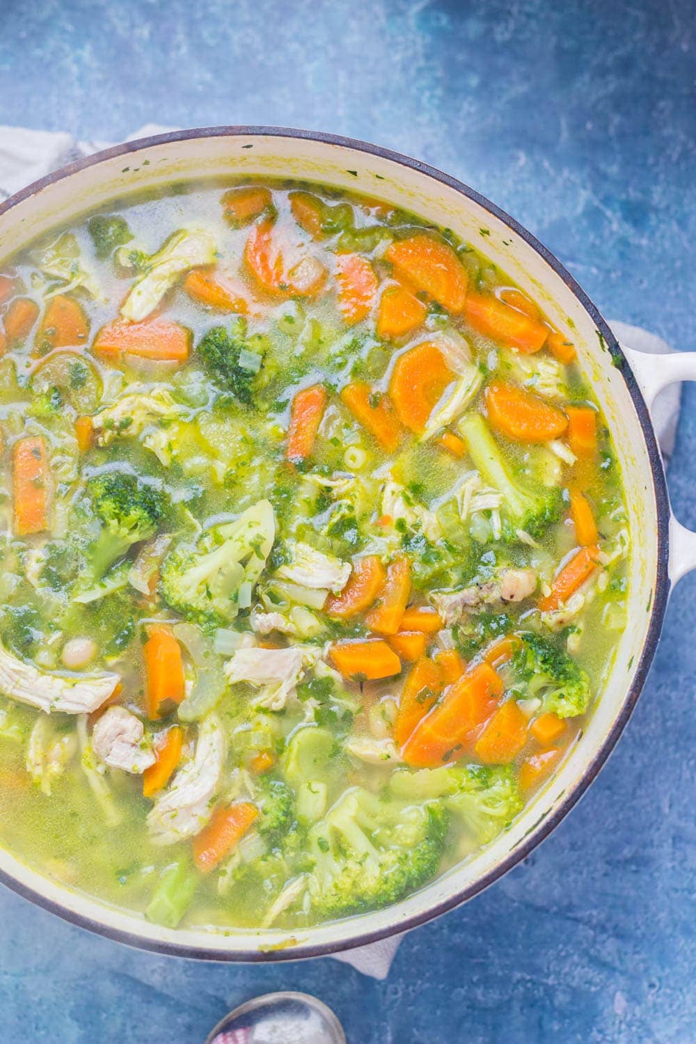 White pot of soup with broccoli and chicken