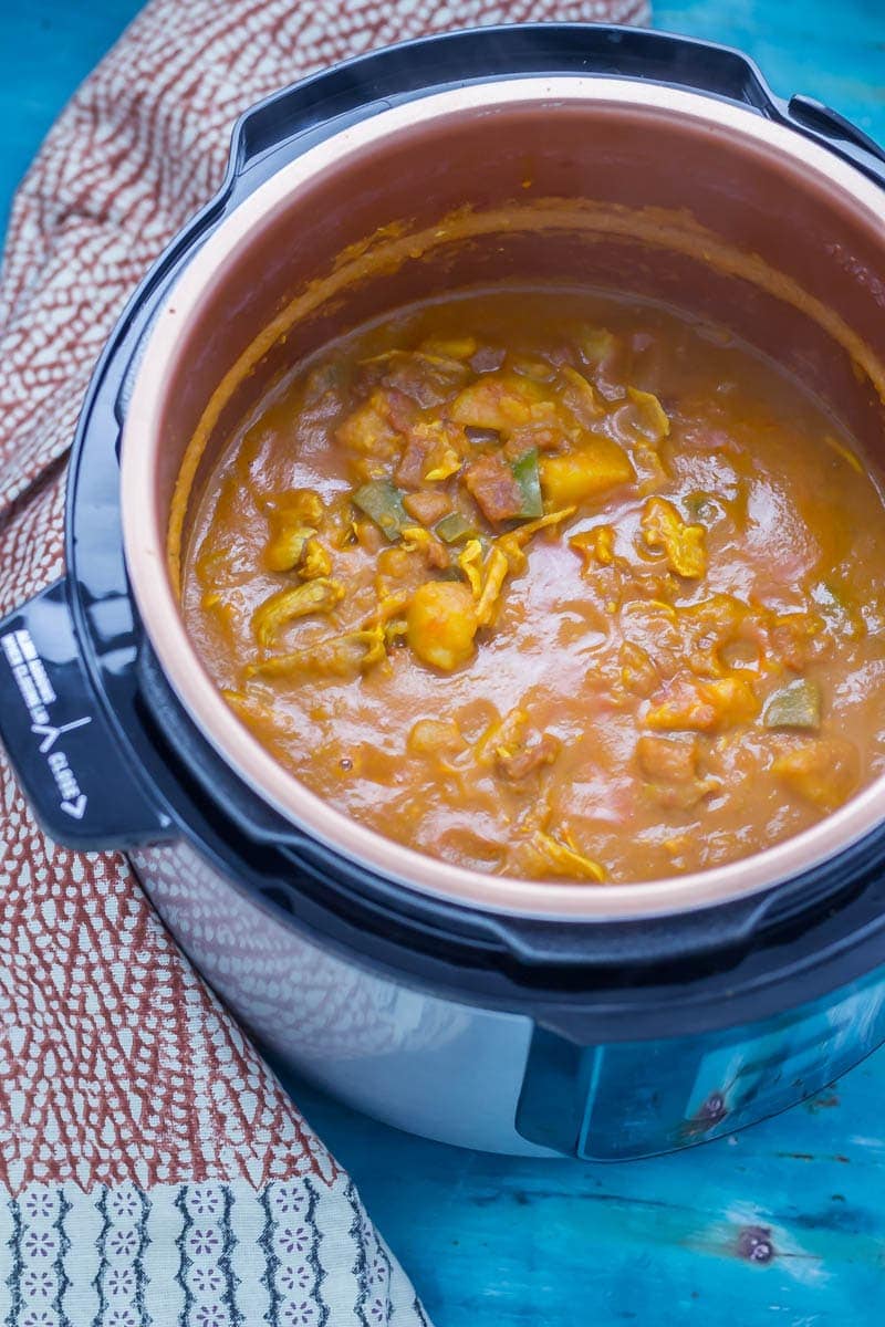 Turkey and potato curry in a pressure cooker over a blue background