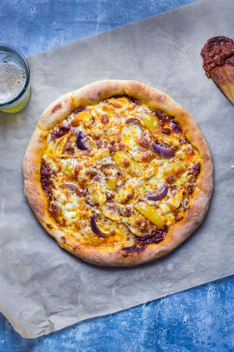 Overhead shot of stuffed crust pizza with chipotle chicken on a baking paper