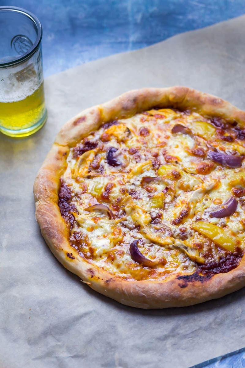 Stuffed crust pizza on baking paper with a glass of beer