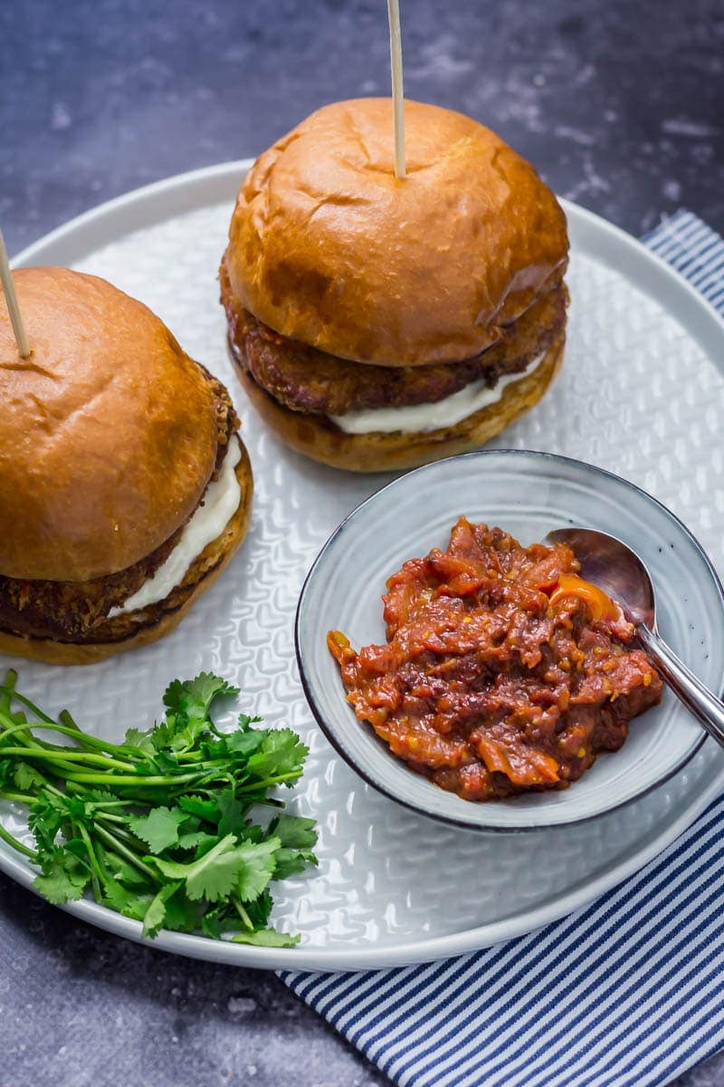 Panko halloumi sandwiches on a grey plate with kasundi and herbs