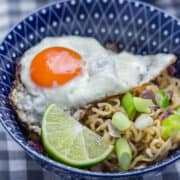 Blue patterned bowl of noodles topped with a fried egg
