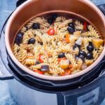 Pasta in a pressure cooker with olives, peppers and red onion