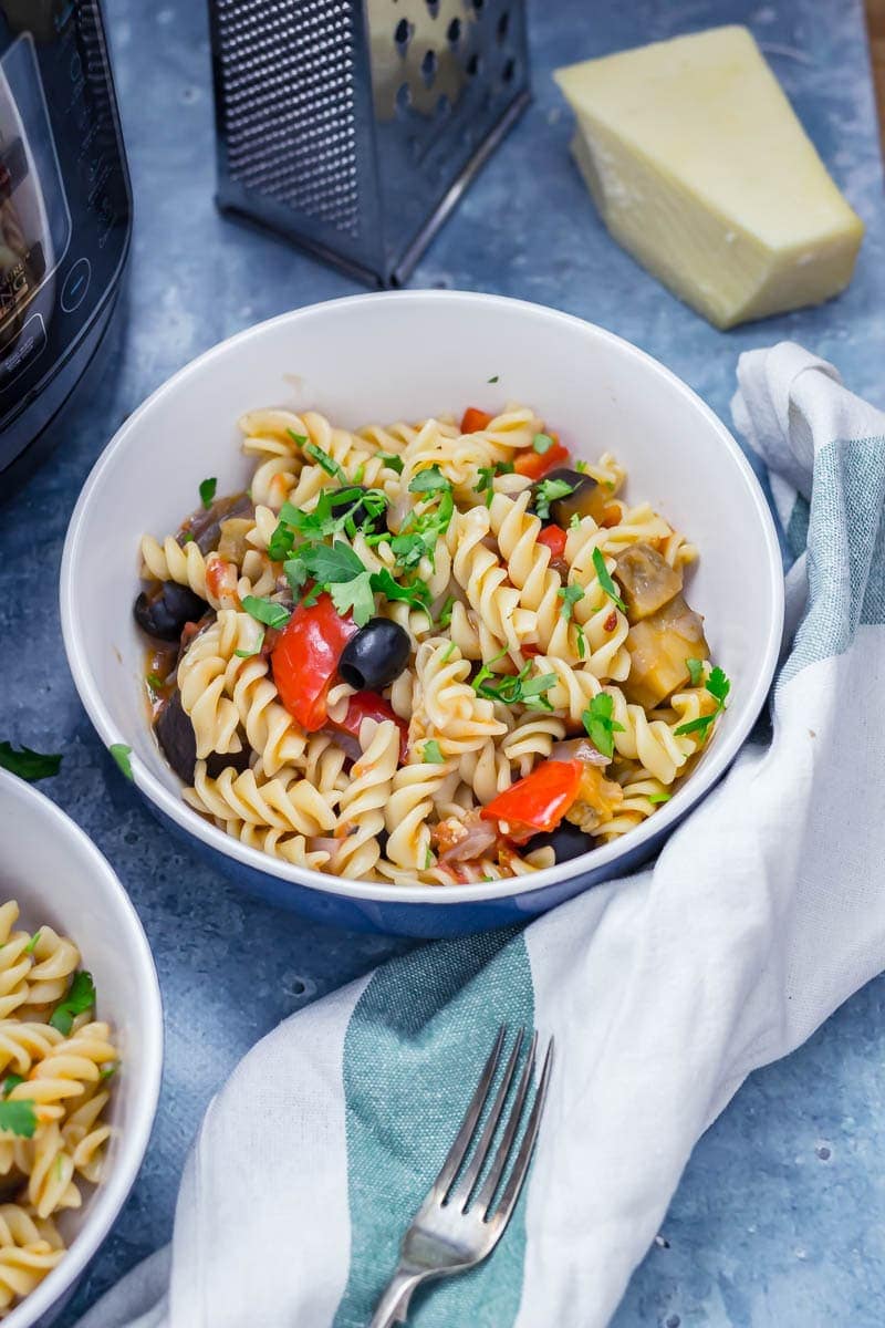 Pressure cooker pasta in a bowl with olives, pepper and aubergine sprinkled with chopped parsley