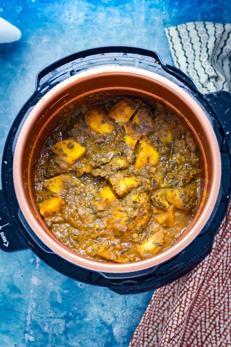 Saag aloo in a pressure cooker with a blue background