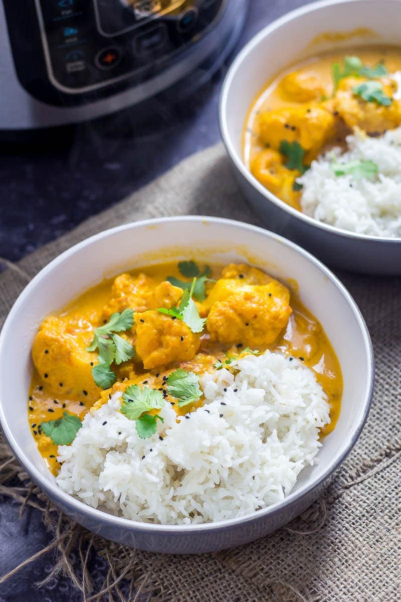 Creamy cauliflower curry in bowls topped with nigella seeds and coriander leaves