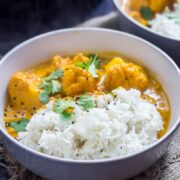 Bowl of creamy cauliflower curry with rice on a hesian mat