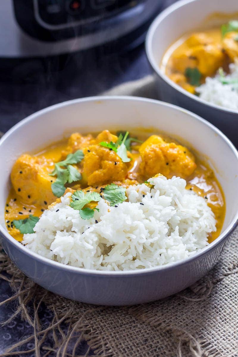 Bowl of creamy cauliflower curry with rice on a hesian mat 