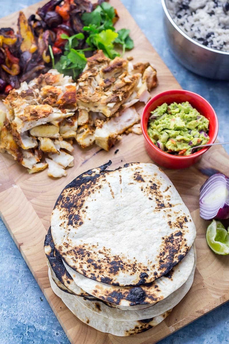 Wooden board on a blue background with fish taco ingredients on it