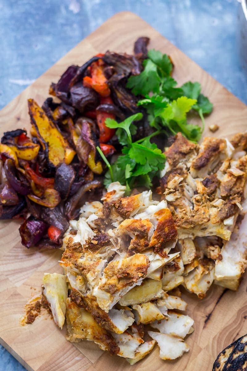 Fish, peppers and red onion on a wooden board on a blue background