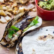 Fish tacos and tortillas on a wooden board