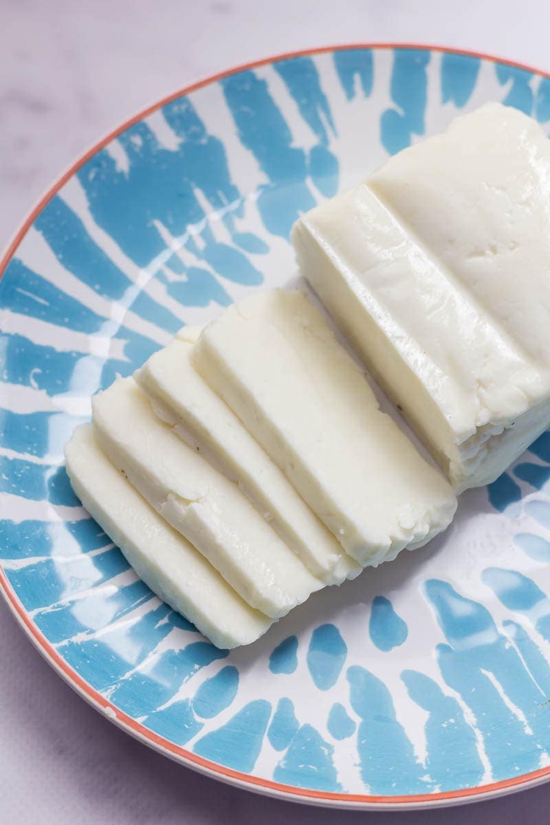 How to cook halloumi. Halloumi cheese sliced on a plate on a marble background