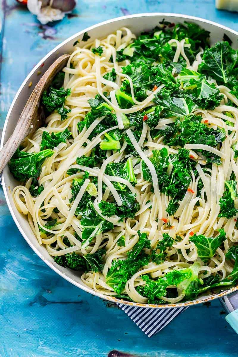 Frying pan of kale pasta on a blue background