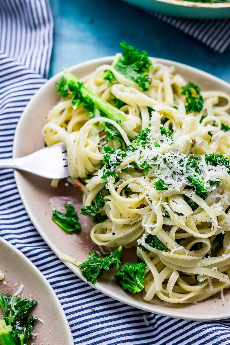 Plate of kale pasta on a striped cloth with a fork