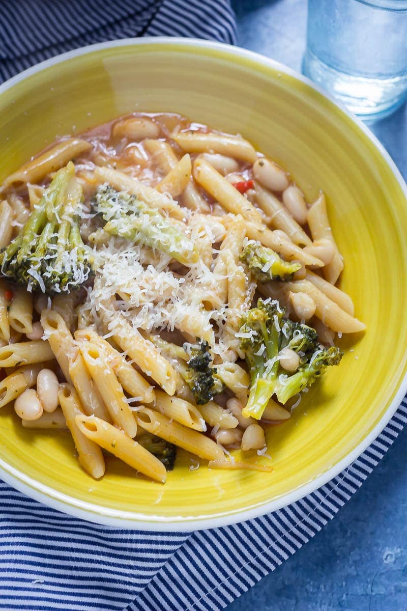 Broccoli and White Bean One Pot Pasta in a yellow bowl on a striped cloth