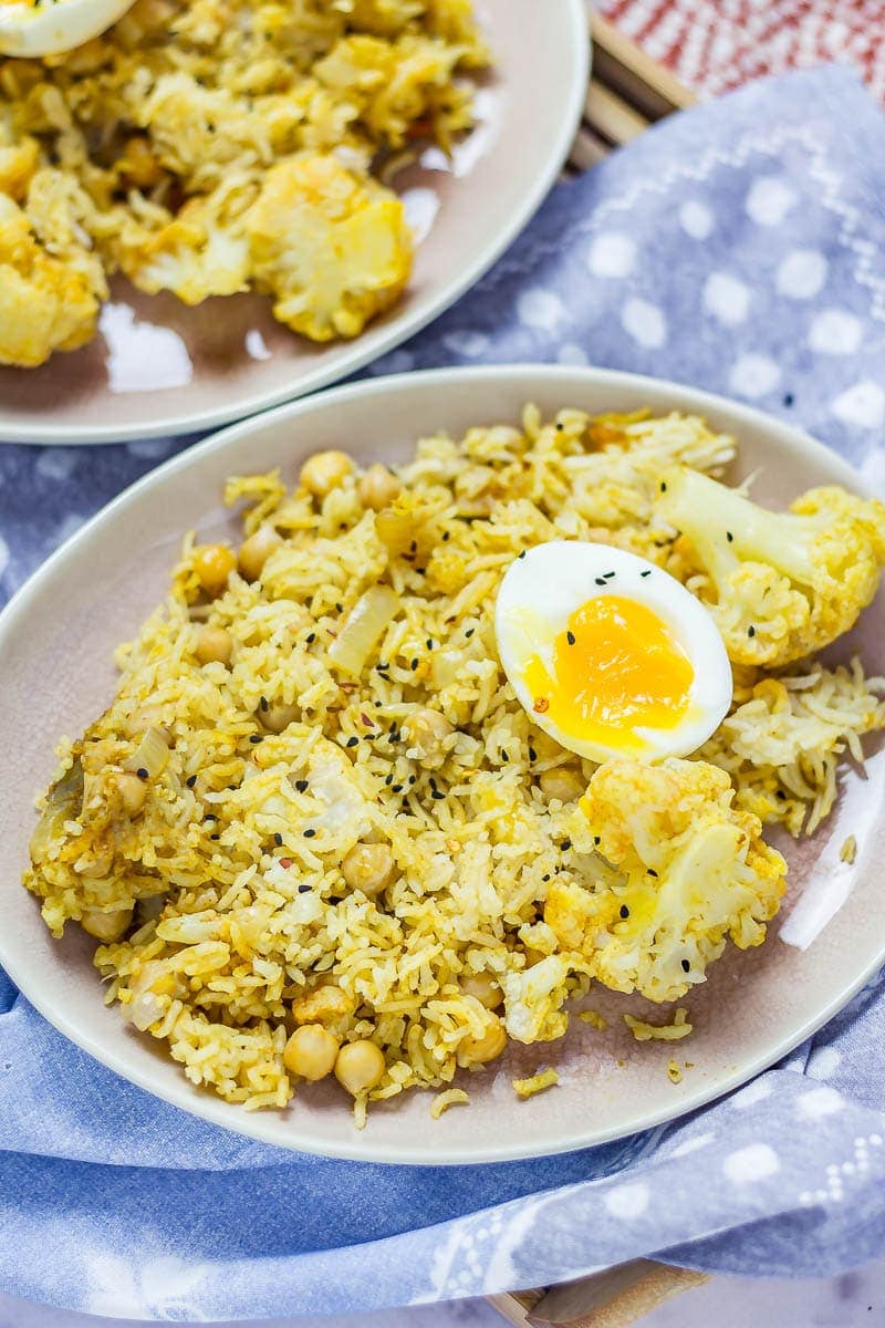 Close up of a plateful of biryani with cauliflower & chickpeas on a blue cloth