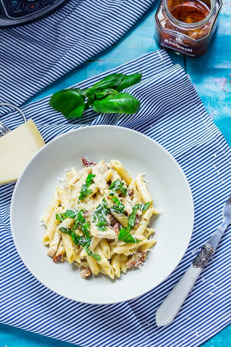 Overhead shot of pressure cooker pasta in a bowl on a striped cloth with a blue background