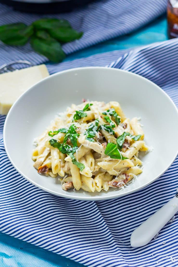 Bowl of creamy chicken pasta on a striped cloth with parmesan