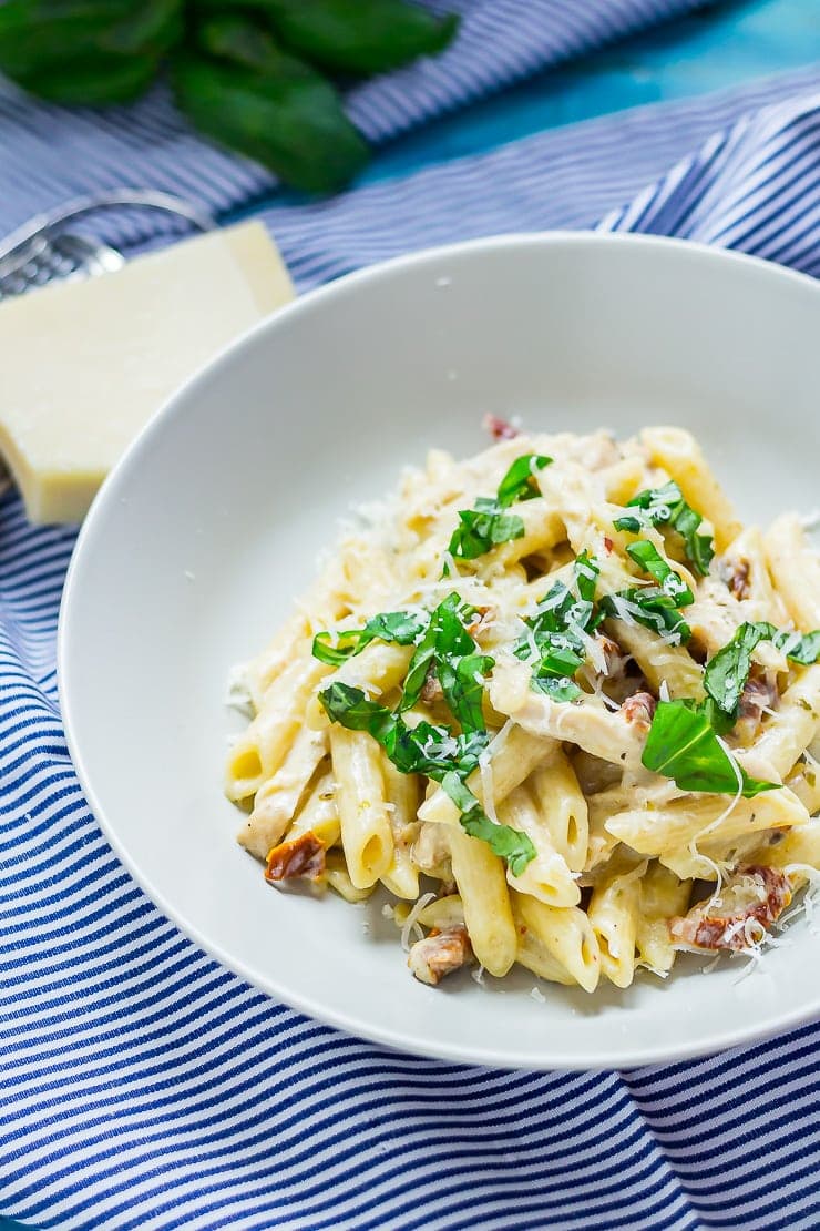 Bowl of creamy chicken pasta on a striped cloth with parmesan