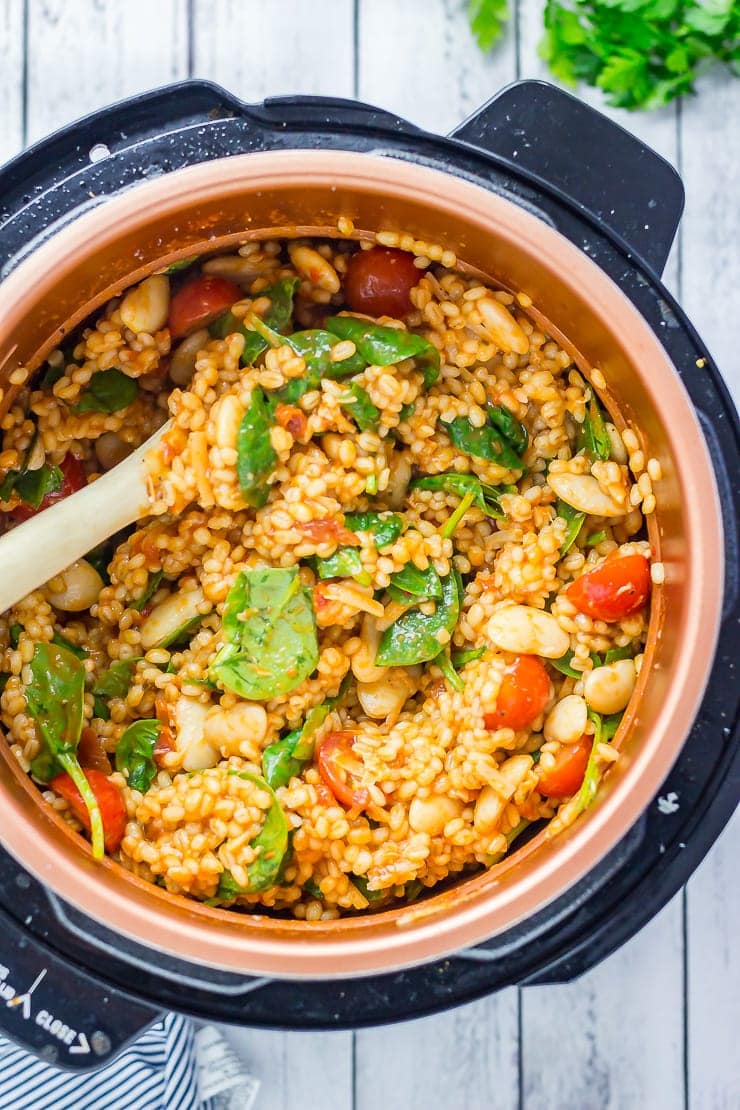 One Pot Cheesy Pearl Barley with Tomatoes in the pressure cooker on a distressed wooden background