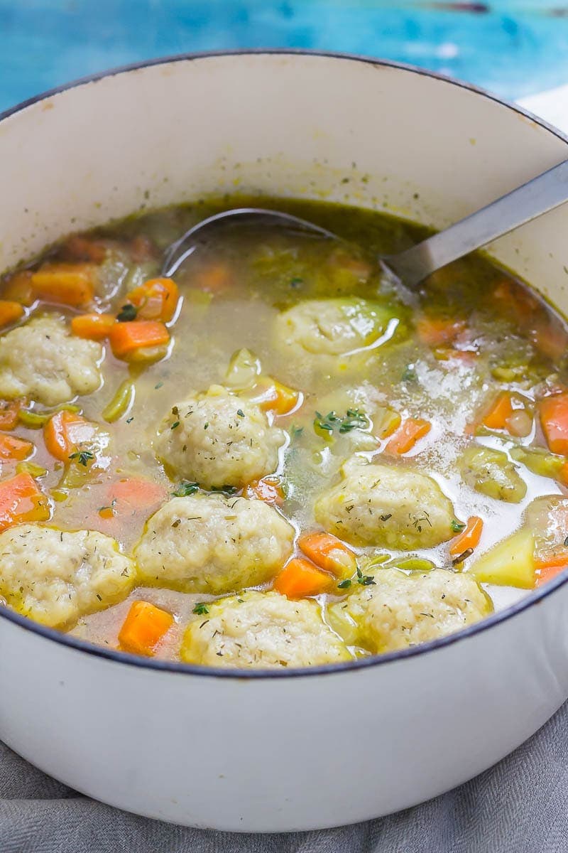 Pot of vegetable soup with dumplings on a blue background