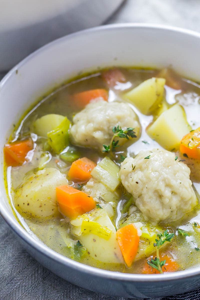 A bowl of Vegetable Soup with Dumplings topped with thyme sprigs