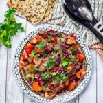 Aubergine Recipes | Overhead shot of Smoky Aubergine Salad with Red Pepper on a white wooden background with bread and parsley