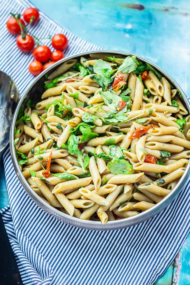 Bowl of pasta salad on a striped cloth over a blue background