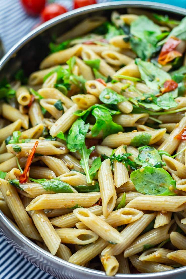 Close up of pasta salad with tomatoes in the background