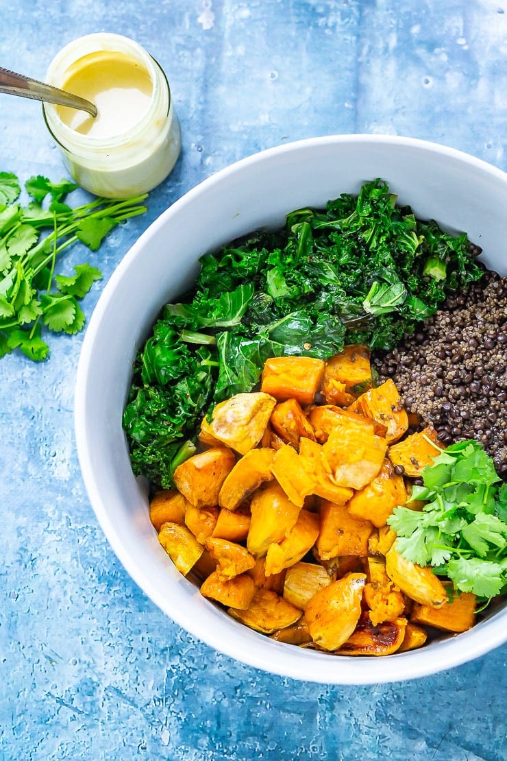 Overhead shot of ingredients for Sweet Potato and Quinoa Salad with Sesame Dressing on a blue background