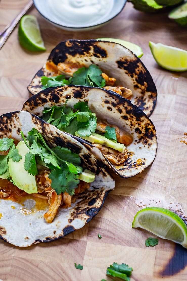 Chipotle chicken tacos on a wooden board with lime wedges