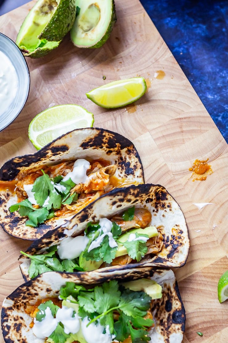 Chipotle chicken tacos on a wooden board on a blue background