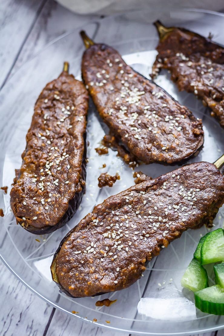 Platter of roasted aubergine with satay sauce on a white wooden background