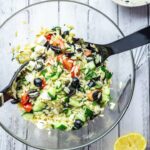 Overhead shot of Greek Orzo Salad with Herby Dressing on a white wooden background