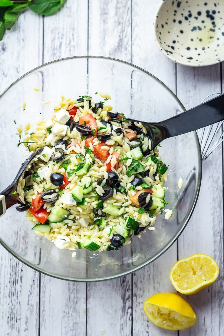 Overhead shot of Greek Orzo Salad with Herby Dressing on a white wooden background