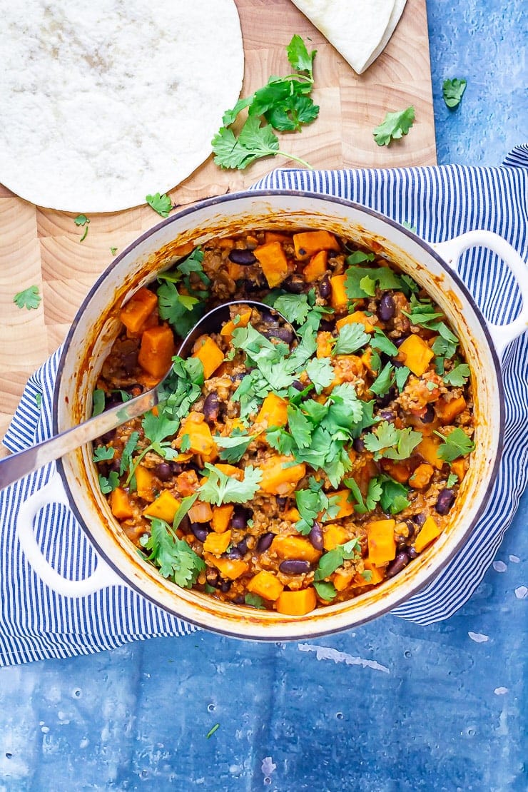 Overhead shot of turkey chilli for burritos on a striped cloth on a blue background