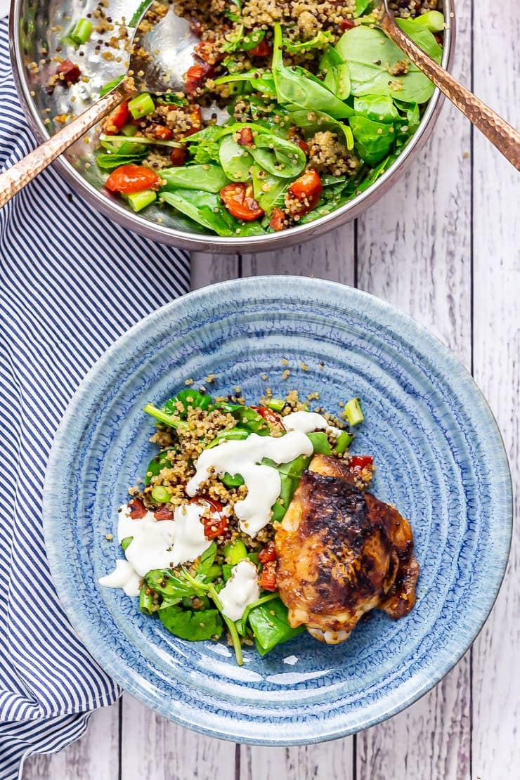 Overhead shot of chipotle chicken salad and quinoa in a blue bowl with a striped cloth on a white wooden background