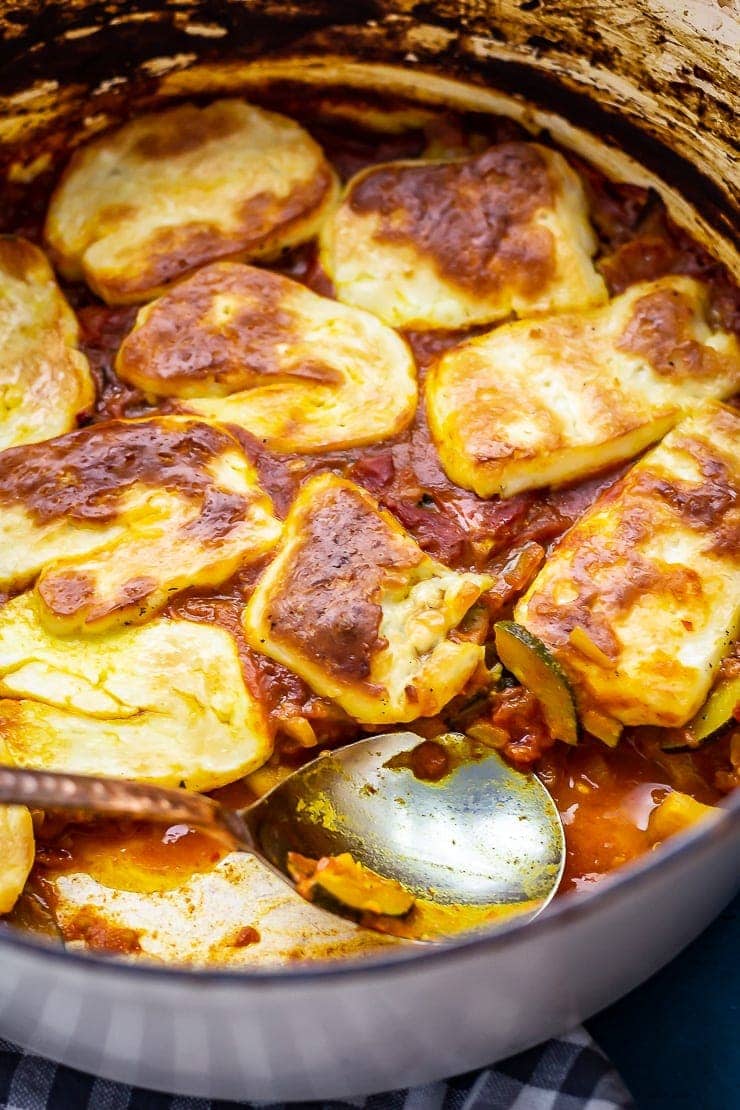 Tomato and halloumi bake with a portion taken and a spoon