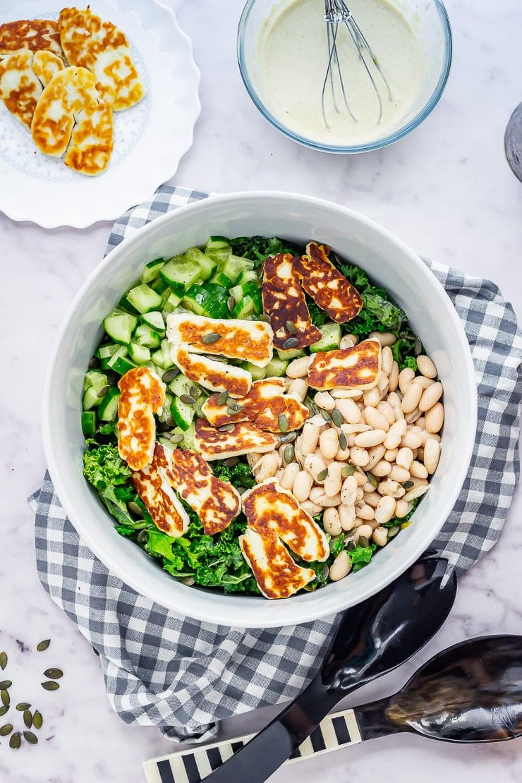 Overhead shot of halloumi salad with kale on a checked cloth on a marble background