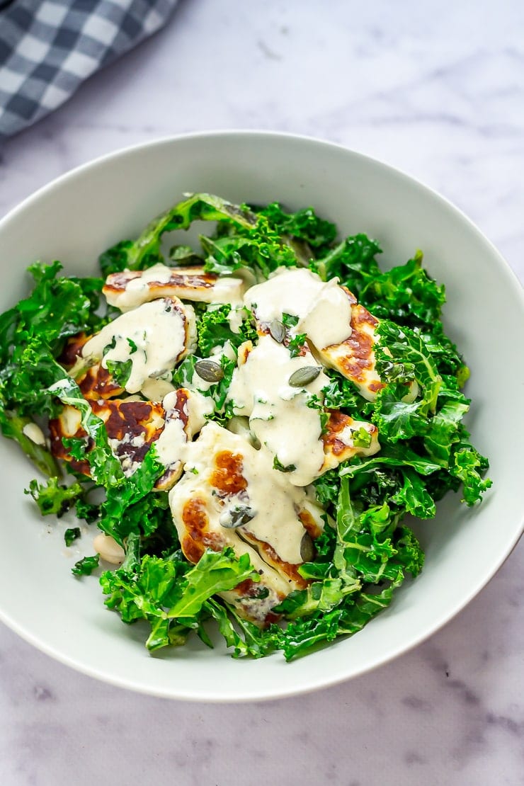 Bowl of halloumi salad with kale on a marble background