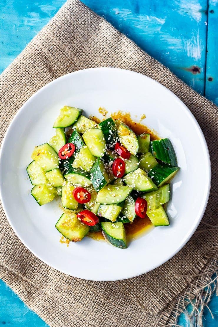 Overhead shot of sesame cucumber salad on a hessian background