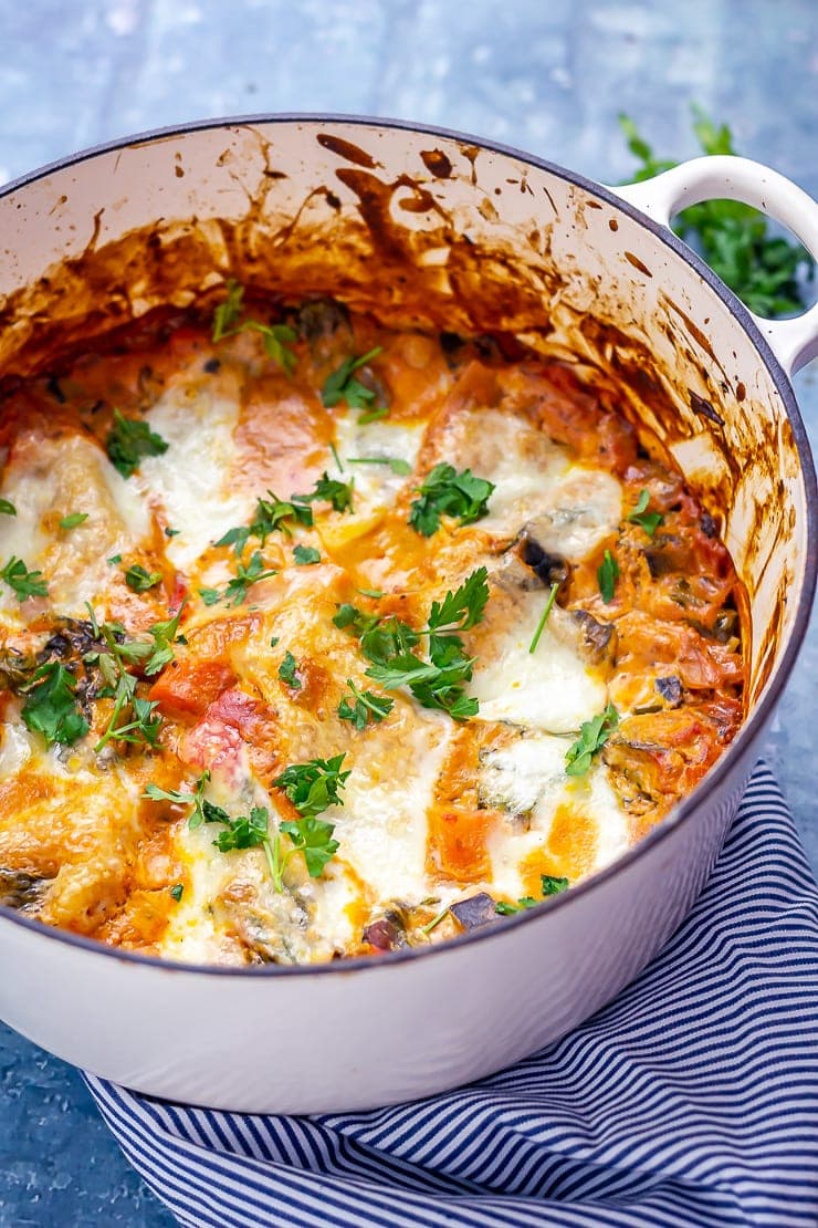 One pot vegetarian lasagne in a white pot on a striped cloth