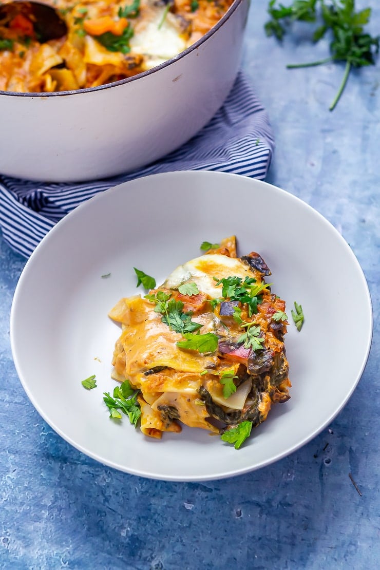 Portion of one pot vegetarian lasagne in a bowl on a blue background