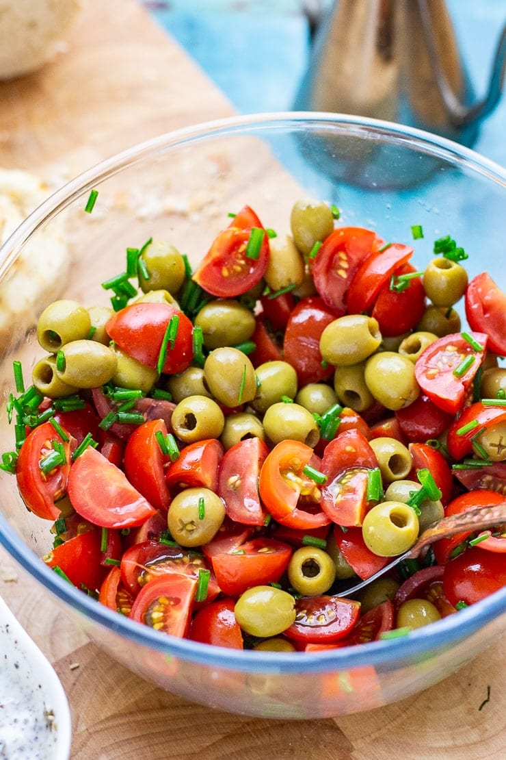 Bowl of olives and tomatoes on a wooden board