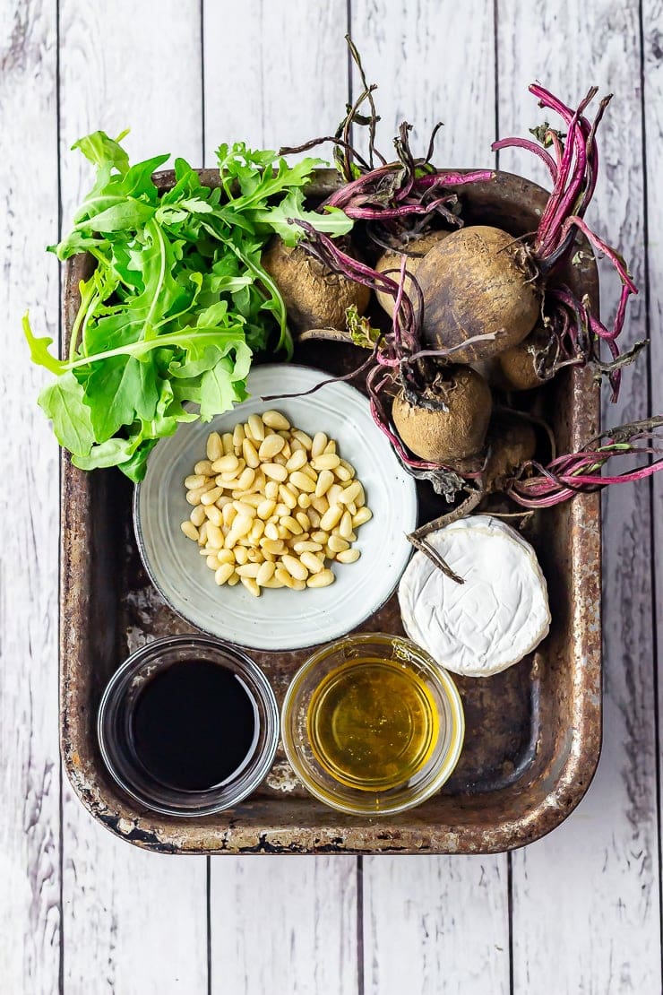 Overhead shot of ingredients for beetroot salad with goat's cheese, balsamic, honey, pine nuts and rocket.